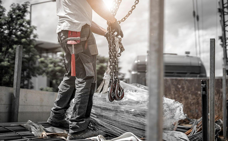 Construction workers unload steel bars from the truck.